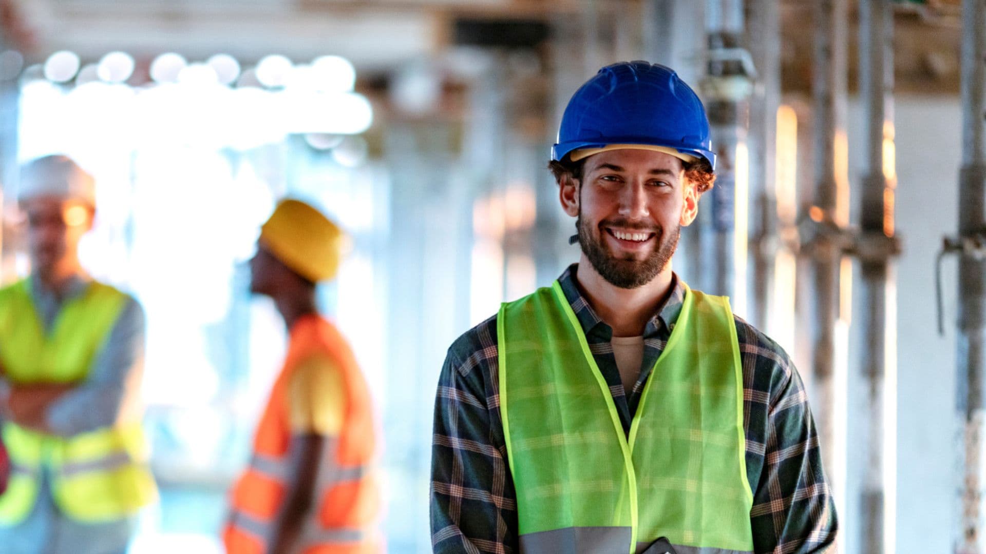 Worker in hard hat and high vis top smiling on worksite
