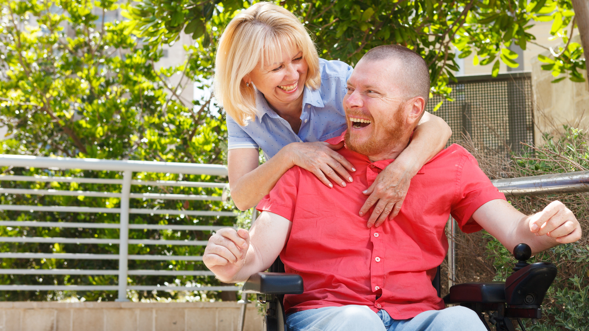 Woman hugs man in a wheelchair and both are laughing