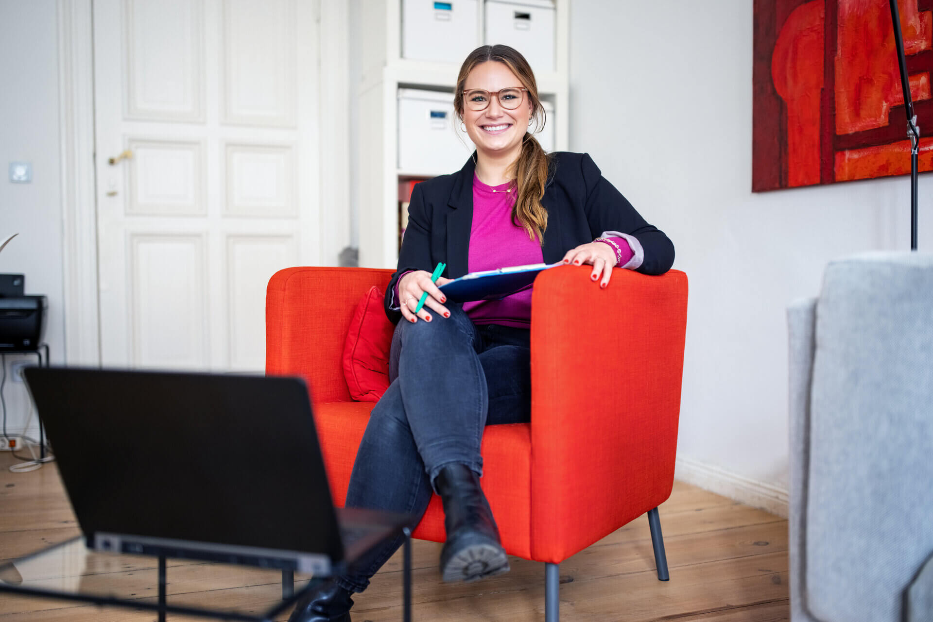 Psychologist sitting on an orange couch with a notepad