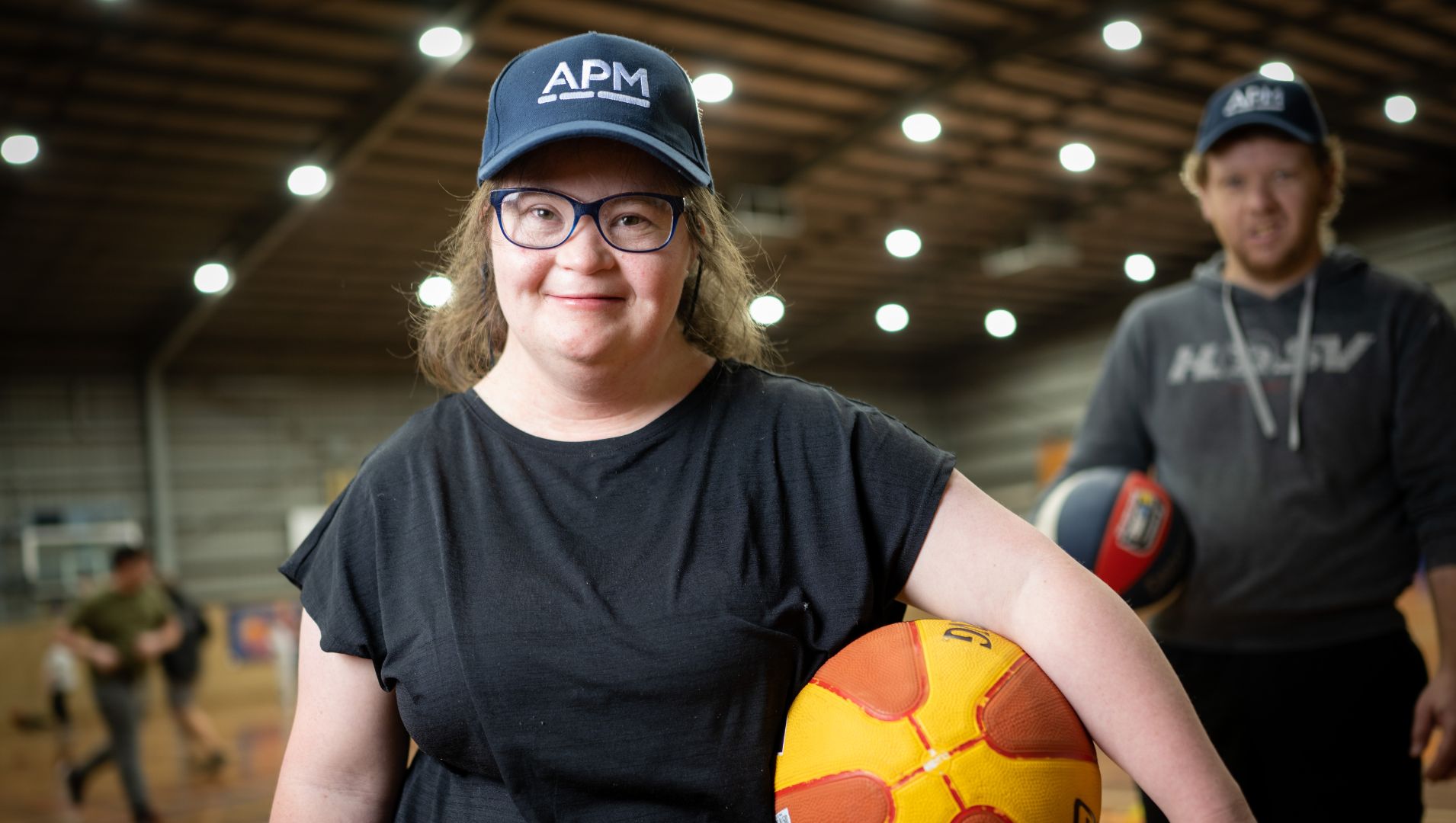 Girl with disability smiling with basketball and APM cap